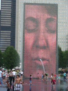 Art installation featuring digital images of faces projected onto glass towers and spouting water